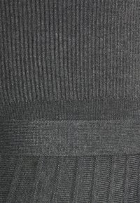 Tissu tricoté gris foncé présentant des côtes verticales et des bandes texturées horizontales avec un motif en chevron le long de la section inférieure.
