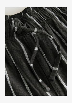 Shorts din țesătură neagră, cu dungi verticale albe, bandă elastică la talie și detaliu cu șnur legat. Material texturat.