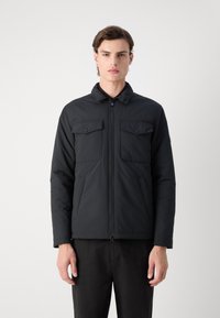 Schwarze gepolsterte Jacke mit einem Reißverschluss vorne, zwei Brusttaschen mit Klappen, Seitentaschen und einem Kragen. Hergestellt aus glattem Material.