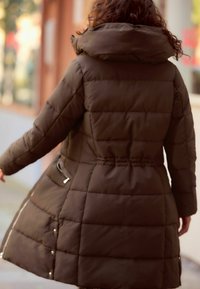 Doudoune marron avec un col haut, dotée de panneaux matelassés et de poches zippées sur les côtés. Le design est mi-long avec une taille cintrée.