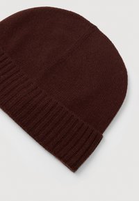 Ciemnobrązowa dziana czapka beanie z prążkowanym mankietem podwiniętym, umieszczona na jasnej, gładkiej powierzchni.