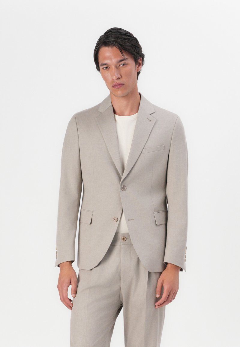 Beige tailored suit made of lightweight fabric, featuring a single-breasted jacket with notch lapels and two front pockets, paired with matching trousers.
