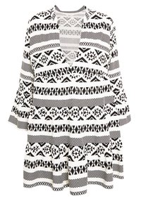 Tunique noire et blanche à motifs avec un col en V, présentant divers dessins géométriques, des manches longues évasées et une silhouette ample et fluide.