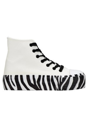 High-Top Sneaker mit einem weißen Canvas-Obermaterial, schwarzen Schnürsenkeln und einer Gummi-Außensohle in Zebra-Streifen schwarz-weiß. Mit einer abgerundeten Zehenpartie.