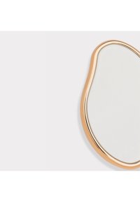 Miroir ovale irrégulier avec un cadre fin et brillant doré sur un fond gris clair.