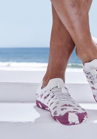 Weiße Strick-Sneaker mit lila Akzenten und strukturierten Mustern, mit einem Slip-On-Design und einer flexiblen Gummisohle.