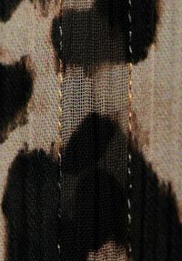 Tela ligera y transparente con diseño de estampado de leopardo en tonos negros y beige, con una malla texturizada negra prominente y detalles visibles de costuras.
