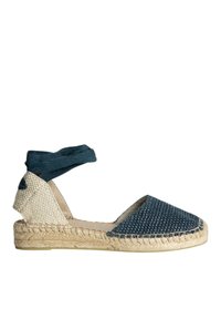 Espadrille de lona azul con textura tejida, suela de yute y una correa de tela en el tobillo. Presenta una punta redondeada y paneles laterales beige.
