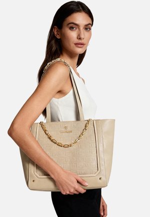 Borsa tote beige con texture granulosa, dettagli in catena dorata e logo. Presenta una forma strutturata e doppi manici a spalla.