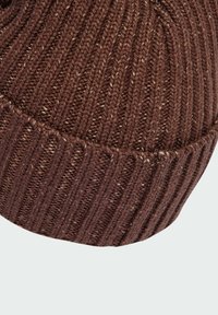 Brown knitted beanie with ribbed texture, featuring a thick cuff. Material appears soft with subtle color variations throughout.