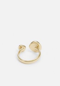 Gouden ring met een gedraaide open bandontwerp. Heeft twee gladde ovale uiteinden met een gepolijste afwerking en een minimalistische stijl.