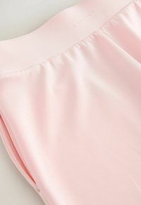 Tissu rose clair avec ceinture élastique, légers fronces sous la taille, et détail de poche sur la couture latérale.