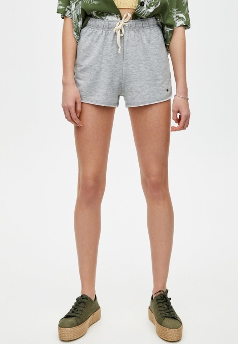 Graue Baumwollshorts mit elastischem Bund und Kordelzug. Glatte Textur. Kombiniert mit olivgrünen, strukturierten Plateausneakern.