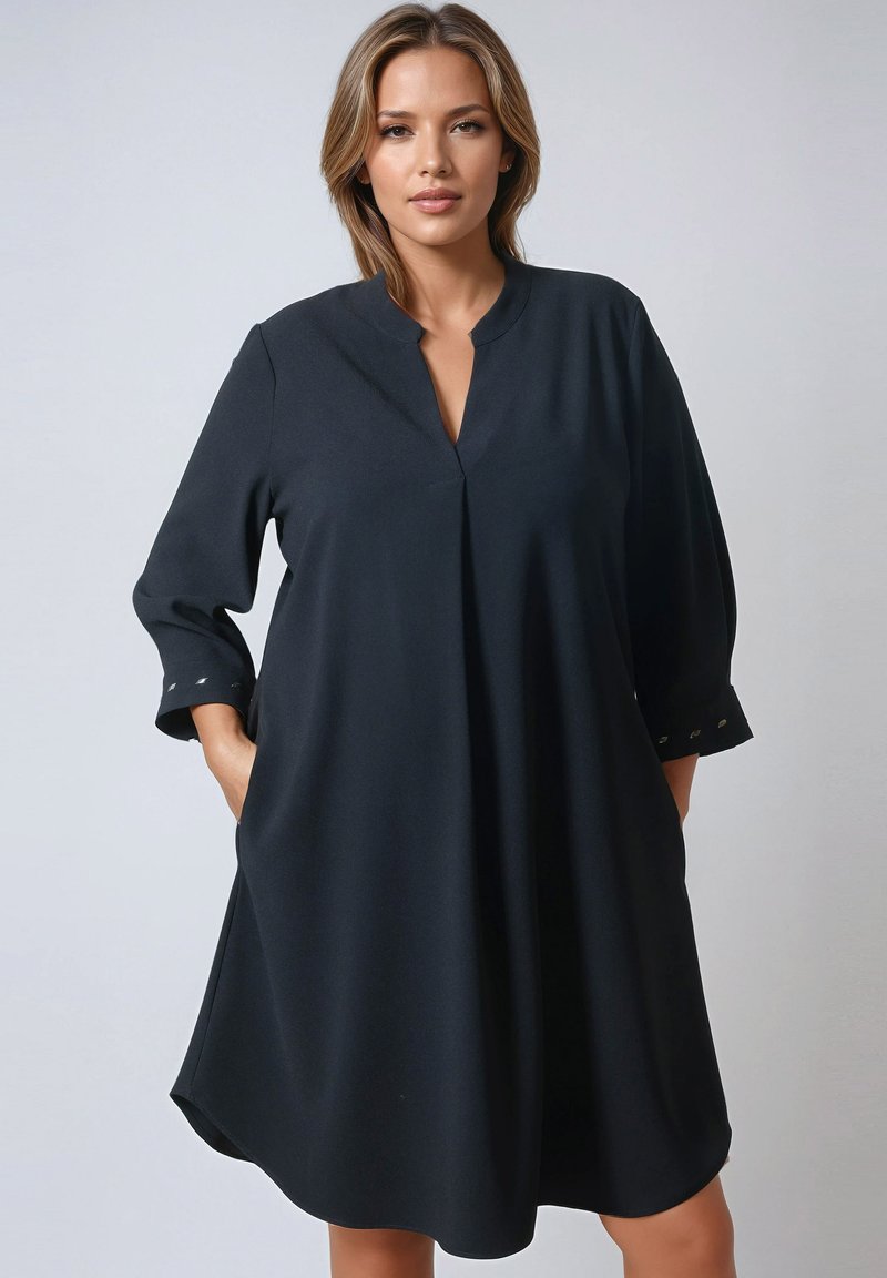 Zwarte tuniek jurk met een V-hals, driekwart mouwen, zijzakken en metalen accenten op de mouwmanchetten. Glad, lichtgewicht stof.