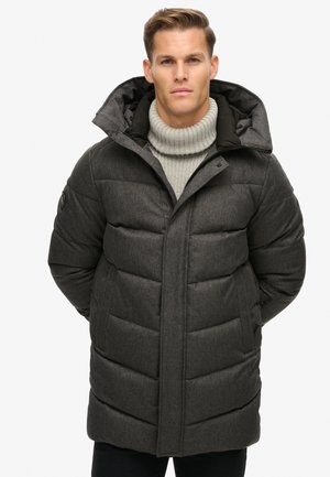 Grijze pufferjas met een gestructureerde afwerking, grote capuchon en verticale gestikte panelen. Voorzien van een ritssluiting aan de voorkant en zijzakken.