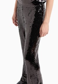 Pantalones de lentejuelas en negro con una textura brillante. El diseño ajustado presenta una cinturilla suave y detalles en las costuras laterales.