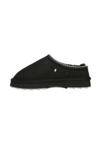 Zapatos negros sin cordones hechos de suave ante con un forro blanco texturizado, que cuentan con un borde de costura contrastante y una suela gruesa y resistente.