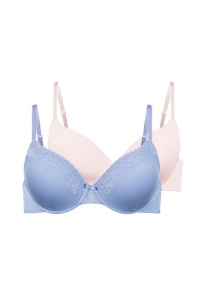 Könnyű kék csipkés melltartót és hozzá illő alsóneműt viselő nő, semleges arckifejezéssel előre néz, egyszínű háttér előtt.