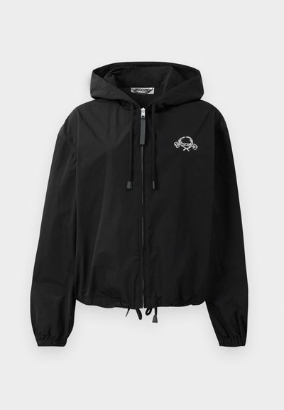 Črna vetrovka z nastavkom za kapuco, elastičnimi manšetami in zadrgo. Ima belo grafično logo na prsih. Lahkoten material.