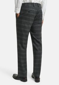 Grijze geruite dresspants met een gladde textuur, rechte snit, zijzakken en een achterzak met knoop, gecombineerd met zwarte loafers.