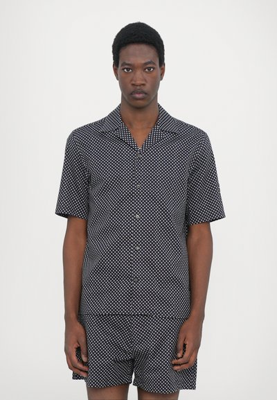 Short-sleeve shirt and shorts set in navy with white polka dots. Made from lightweight fabric, featuring a button-down front and pointed collar.
