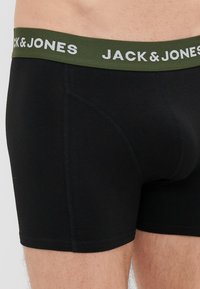 Μαύρο βαμβακερό σλιπ μποξέρ με ελαστική μέση ελιάς που φέρει την ένδειξη "JACK & JONES" σε άσπρο χρώμα. Λείος υφασμάτιος χαρακτήρας και εφαρμοστή σχεδίαση.