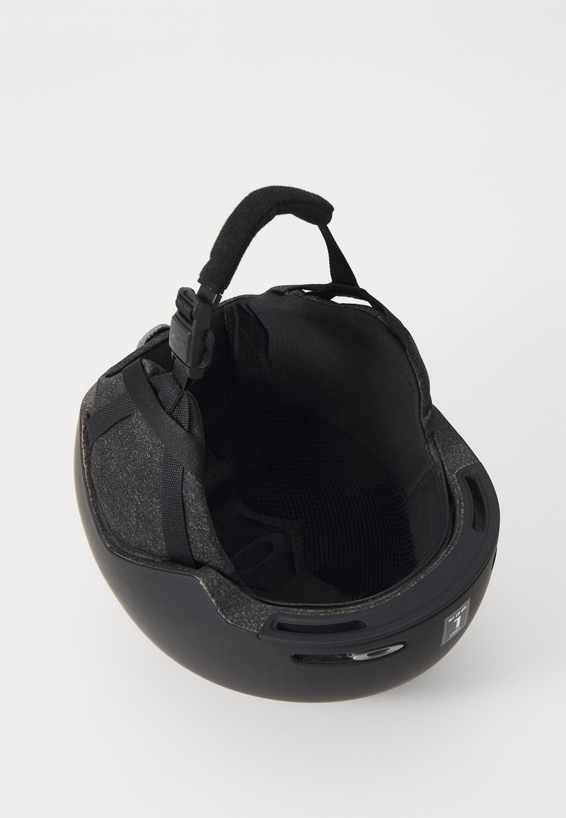 Svart hjälm med en slät yta, vadderat innertak och justerbart band. Har ventilationshål och vadderat haka-band för komfort.