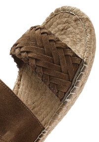 Sandalo in suede marrone con tomaia intrecciata, suola in juta e dettagli cuciti. Presenta una suola piatta e un design open-toe.