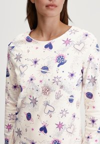 Maglietta bianca a maniche lunghe con un modello colorato di cuori, stelle, pianeti e cristalli in tonalità di rosa, blu e viola. Tessuto morbido, scollatura rotonda.