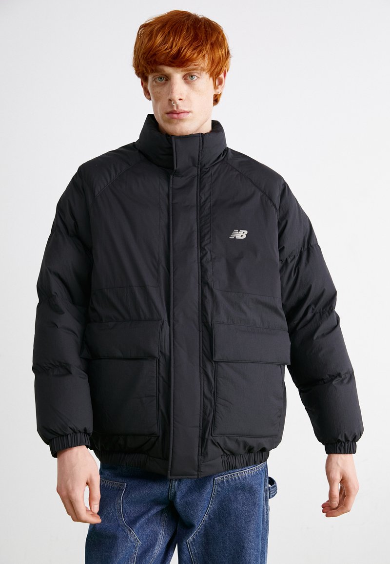 Schwarze Steppjacke mit hohem Kragen, elastischen Bündchen, zwei Fronttaschen und einem dezenten Logo auf der Brust. Hergestellt aus einem glänzenden, strapazierfähigen Material.