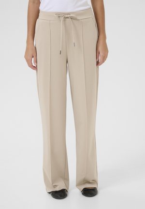 Beige wide-leg trousers with a drawstring waist, featuring front pleats and a smooth, lightweight fabric. Accented with black shoes.