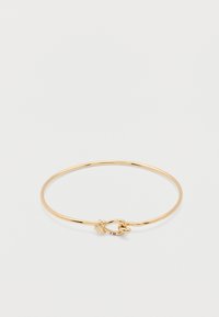 Λεπτό χρυσό βραχιόλι με μικρό κρίκο και κόμπο κούμπωμα σε απλό λευκό φόντο.