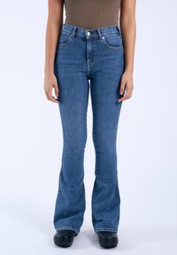 Jeans acampanados de tiro alto en denim azul medio, con bolsillos frontales, cierre de botón y detalles de costura sutiles.