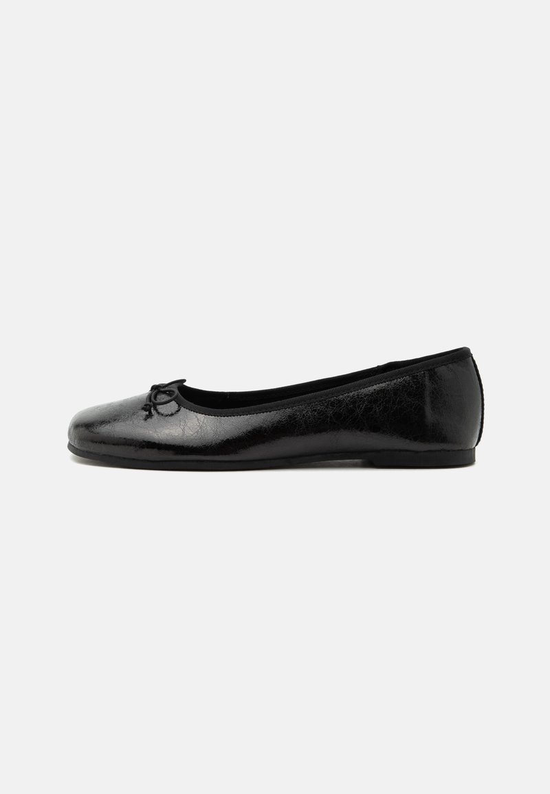 Ballerine en cuir noir brillant avec petit talon et petit nœud décoratif sur l'avant, vue de côté sur fond clair uni.