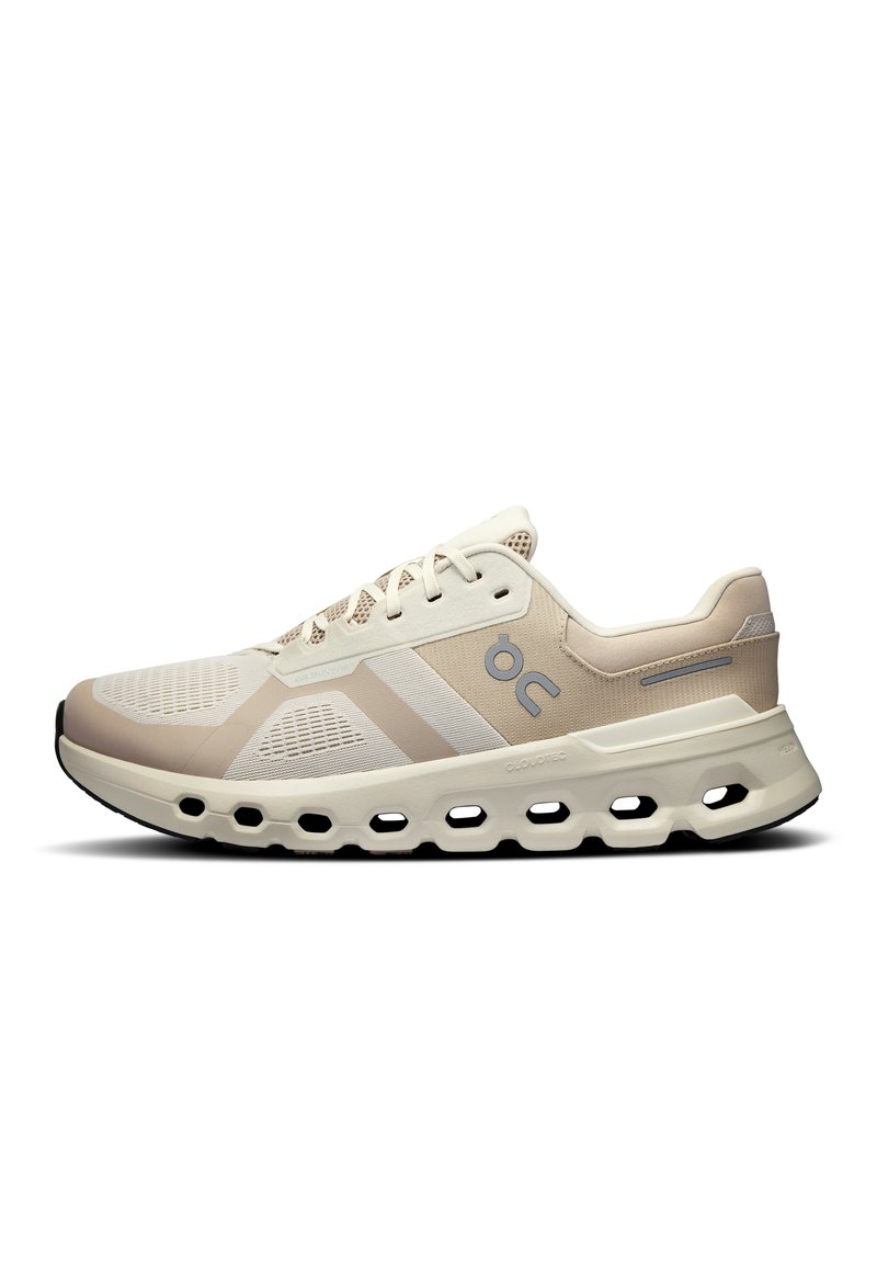 Zapatillas deportivas beige con una parte superior de malla transpirable, sutiles acentos blancos y una suela acolchada con recortes distintivos para mayor flexibilidad.