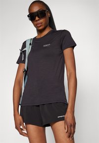 Czarny t-shirt z krótkim rękawem, wykonany z lekkiego materiału, z małym logo Patagonia na klatce piersiowej. Połączony z czarnymi szortami.