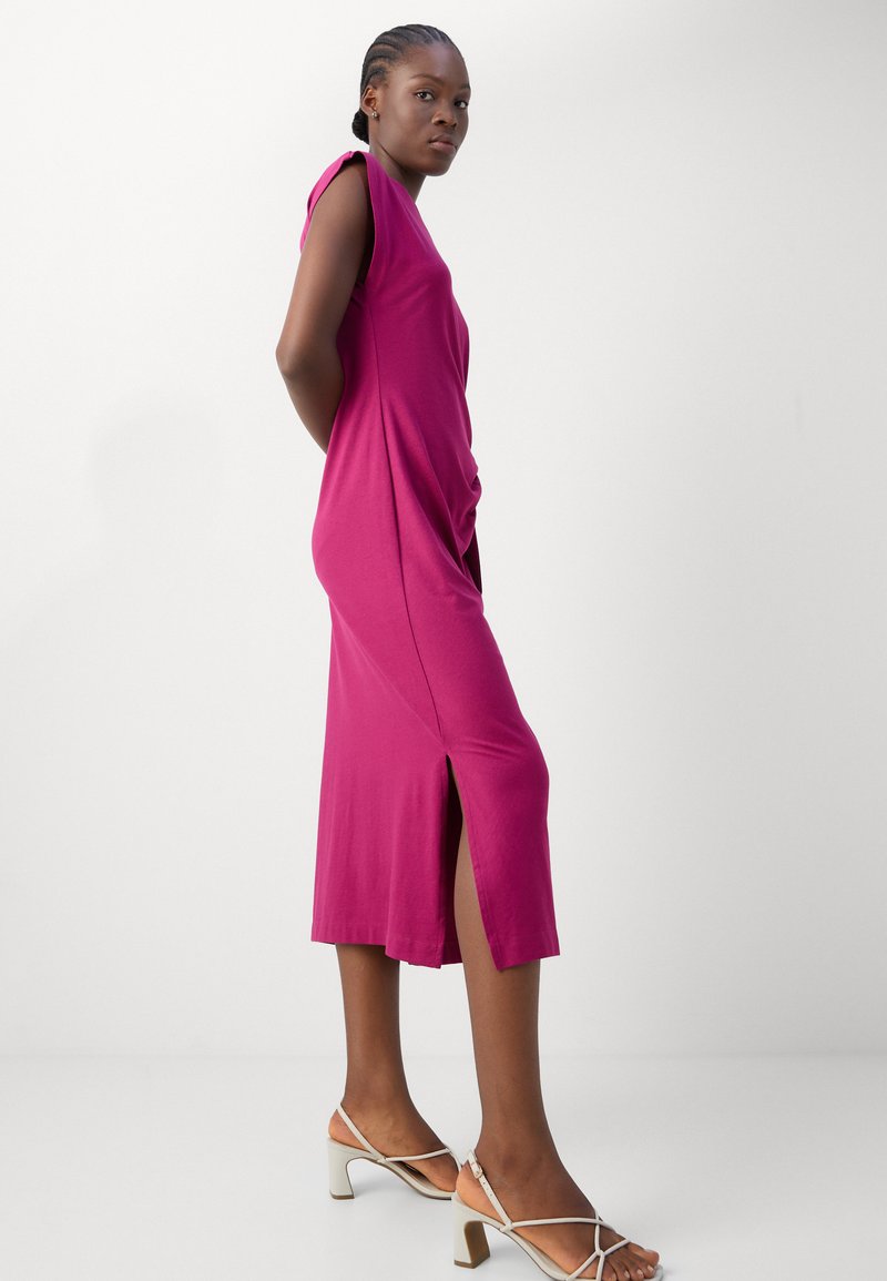 Fuchsia Slinky-Kleid, midi-länglich mit seitlichem Schlitz, lockere Passform und kurzen Ärmeln. Kombiniert mit leichten, strappy Absätzen und einem sanften Hautton.