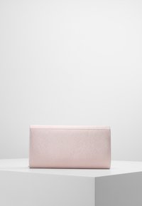 Metaliczna różowa kopertówka o gładkiej fakturze i prostokątnym kształcie. Charakteryzuje się prostym designem z przeszyciami wzdłuż krawędzi.