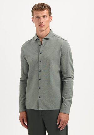 Grau langärmliges Hemd aus strukturiertem Stoff, mit einem Button-Down-Kragen und dunklen Knöpfen, kombiniert mit dunklen Hosen.