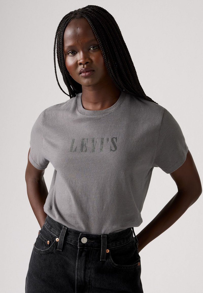 Szürke pamut póló rövid ujjakkal és kerek nyakkal, a mellkasán sötétzöld "LEVI'S" logóval.