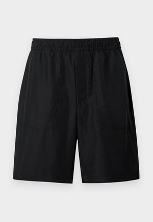 Shorts taille élastique noire avec deux poches plaquées à l'avant et une coupe droite arrivant au genou, sur un fond uni.