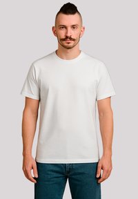 White cotton t-shirt with a round neckline and short sleeves, featuring a relaxed fit and smooth texture, worn with blue denim jeans.