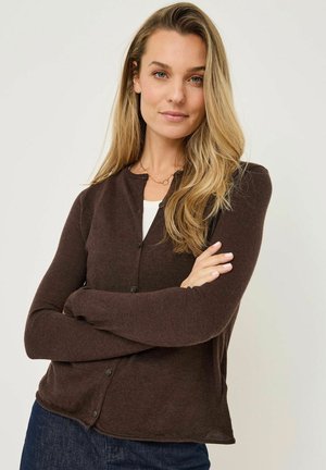 Brauner Strickcardigan mit rundem Ausschnitt, langen Ärmeln und vorderer Knopfverschluss, kombiniert mit einem weißen Oberteil darunter.