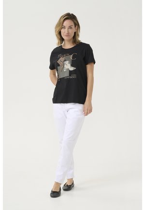 T-shirt noir avec impression graphique, manches courtes et col rond associé à un pantalon blanc et des ballerines noires. Texture de tissu lisse.