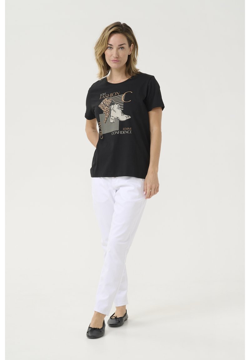 T-shirt noir avec impression graphique, manches courtes et col rond associé à un pantalon blanc et des ballerines noires. Texture de tissu lisse.