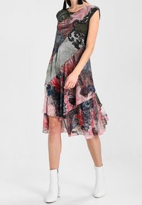 Robe multicolore avec un design en couches présentant des motifs floraux et géométriques, manches courtes et ourlet fluide.