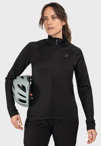Schwarze Zip-Jacke aus weichem, atmungsaktivem Material mit langen Ärmeln. Kombiniert mit einem hellgrünen Fahrradhelm, der ein schlankes Design aufweist.