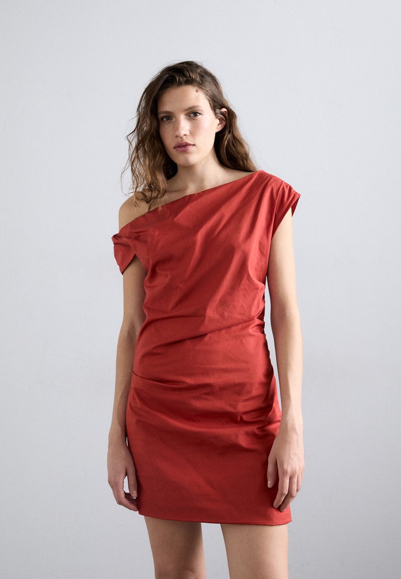 Rochie roșie off-the-shoulder din bumbac, cu un design ajustat, drapaje și mâneci scurte, textură netedă și lungime mini.
