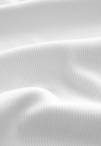 Vit ribbad tyg med fina vertikala linjer, som visar en slät yta och lätt glans, draperad i mjuka vågor.