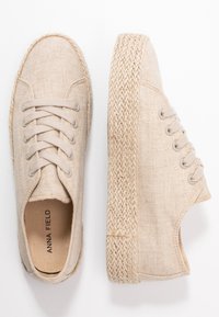 Beige espadrille kengät, jotka on valmistettu teksturoidusta kankaasta, ja joissa on kudottu juutti-pohja, pyöreä kärki ja narulla suljettava malli metallisilla silmukoilla.